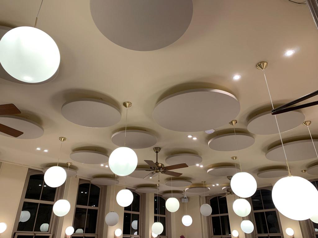 Circle acoustic panels suspended from the ceiling in a fine dining restaurant